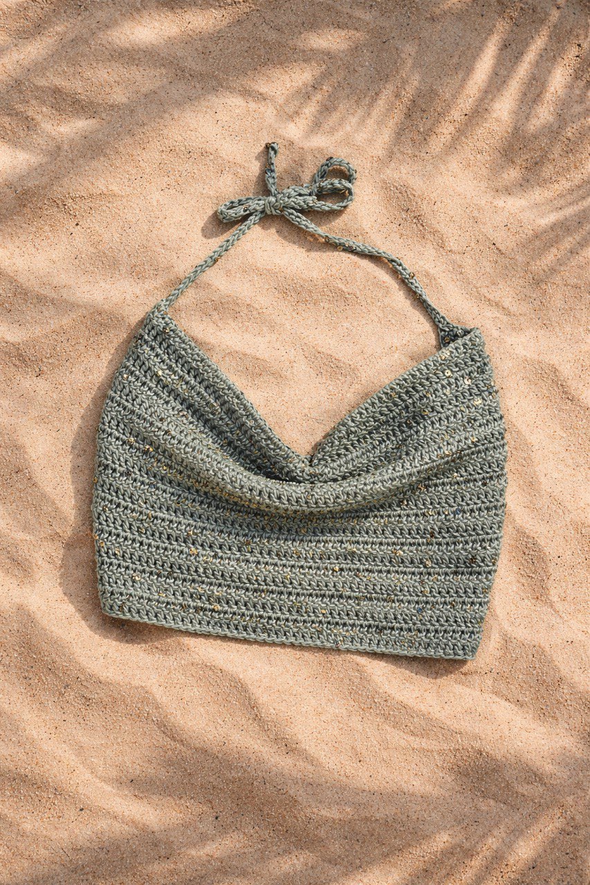 Crochet halter crop top handmade laid on sand, boho summer vibe