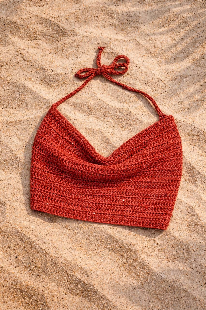 Crochet halter crop top handmade laid on sand, boho summer vibe