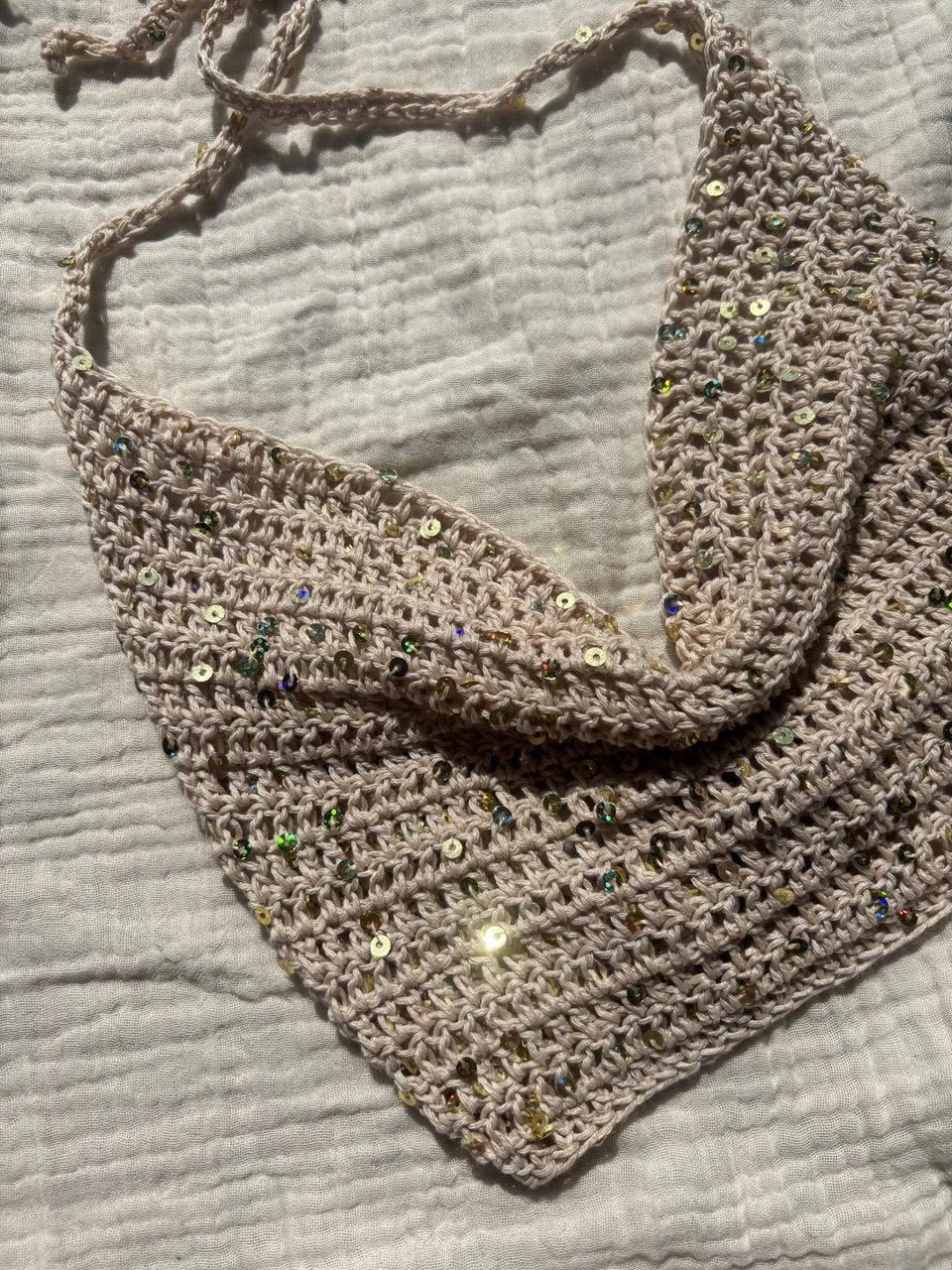Crochet halter top white sand appoggiato su telo bianco con luce naturale. handmade in Italy