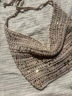 Crochet halter top white sand appoggiato su telo bianco con luce naturale. handmade in Italy