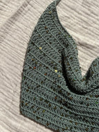 Crochet halter top white sand appoggiato su telo bianco con luce naturale. handmade 
