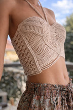 Corsetto in macramé color panna realizzato a mano, con lavorazione artigianale a nodi e design strutturato. Il top avvolge il corpo con una vestibilità regolabile, esprimendo uno stile boho naturale ed elegante.